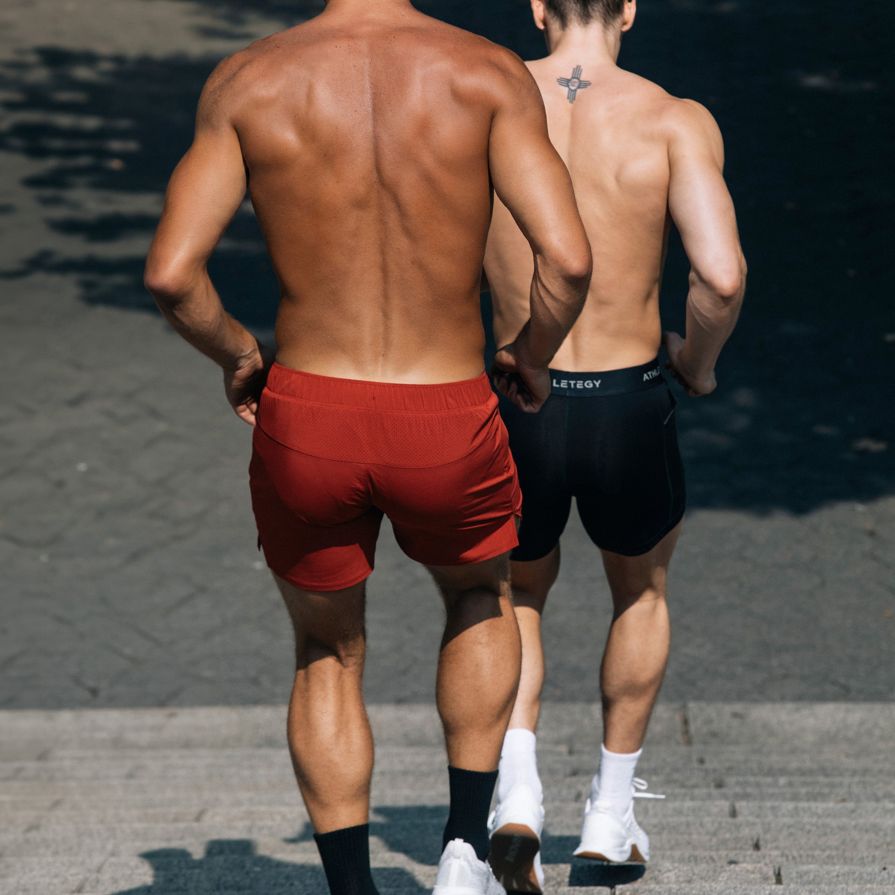 Two men standing in gym clothes in a gym